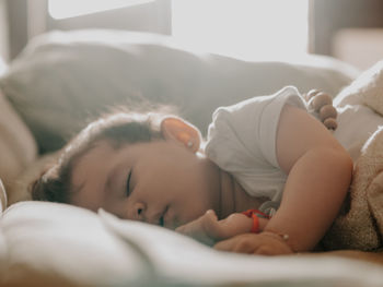 9 month old baby sleeping under warm natural light