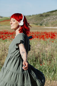 Full length of a smiling young woman standing on field
