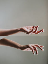 Close-up of woman hand against gray background mirror