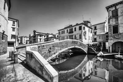 Bridge over canal amidst buildings in city against sky