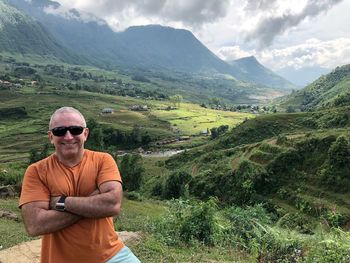 Portrait of man standing on field against mountains