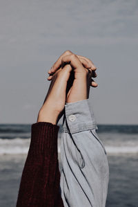 Cropped image of women holding hands at beach