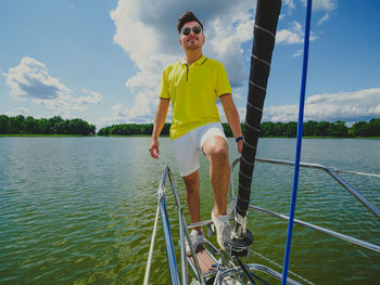 Handsome young person standing on a sailboat bow and looking at front in sunny summer day person