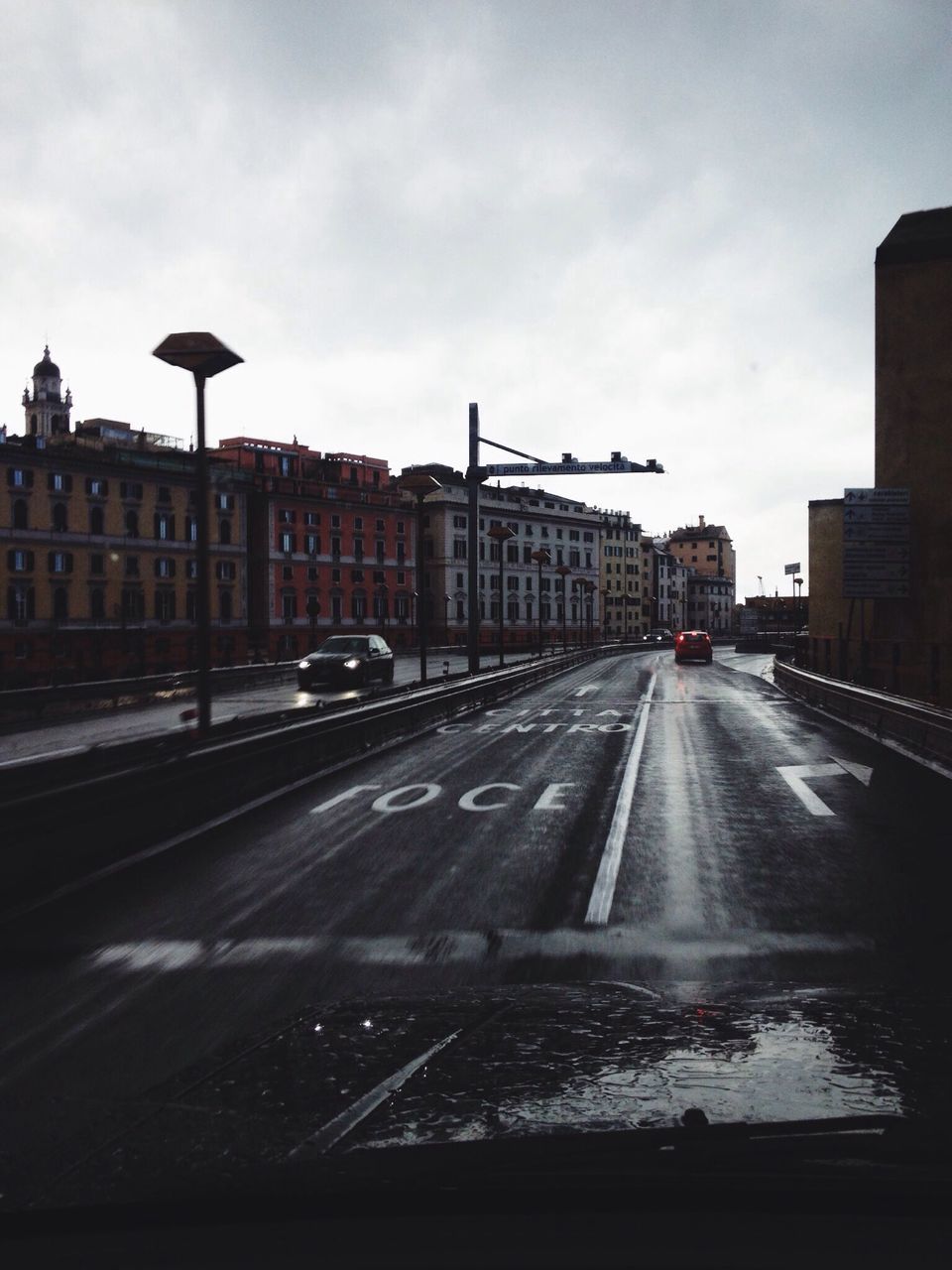 transportation, architecture, mode of transport, built structure, car, road, land vehicle, building exterior, sky, road marking, the way forward, city, street, diminishing perspective, travel, on the move, vanishing point, railroad track, public transportation, cloud - sky