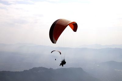 Silhouette person paragliding against sky