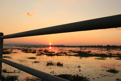 Close-up of silhouette railing against sky during sunset