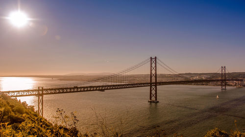 View of suspension bridge over river at sunset