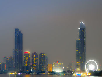 Illuminated buildings in city against sky at night