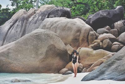 Rear view of shirtless man on rock at sea