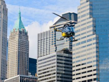 Low angle view of helicopter flying against buildings in city