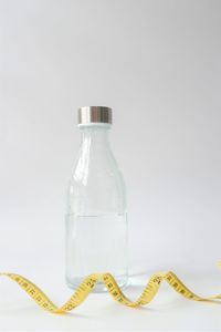 Close-up of glass bottle on table against white background