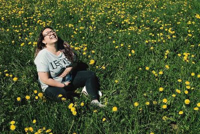 Young woman sitting on yellow flower in field