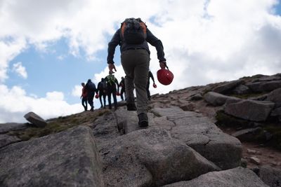 People on rock against sky