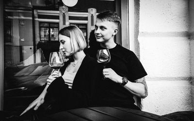 Man and woman drinking glass while sitting in kitchen