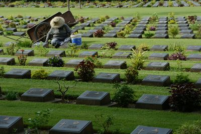 Man sitting amidst tombstones in cemetery