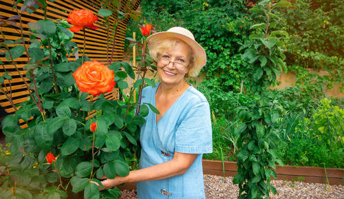 Portrait of smiling woman standing by plants