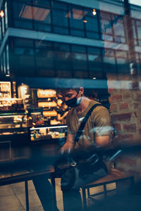 Young man wearing mask sitting at cafe