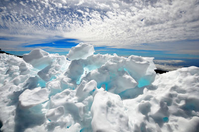 Scenic view of snow covered mountains against cloudy sky