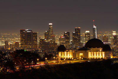 Griffith observatory at night with the los angeles skyline in the distance