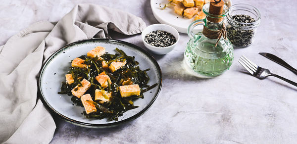 Vegetarian fried tofu and seaweed salad on a plate on the table web banner