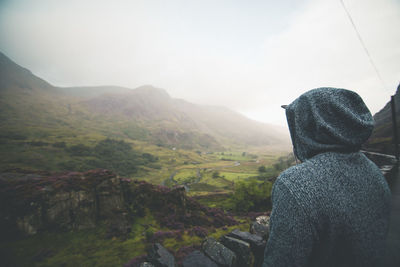 Rear view of man looking at mountains against sky