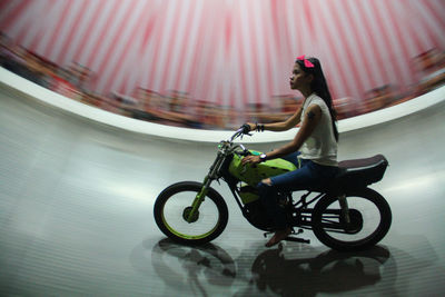 Young woman riding bicycle in wall of death