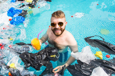 Portrait of smiling man with garbage in swimming pool