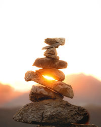 Close-up of stone stack on rock against sky during sunset