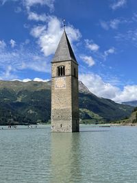 Tower of building by mountain against sky