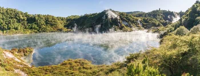 Panoramic view on huge boiling geothermal lake surrounded by lush green foliage, new zealand