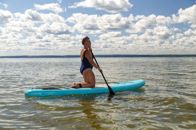 Rear view of woman in boat in sea against sky