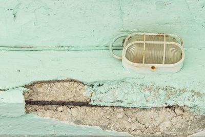 Low angle view of lighting equipment on weathered wall