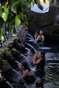 Group of people sitting on rock by water