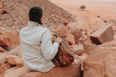 Rear view of man sitting on rock