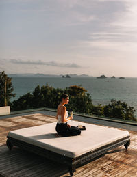 Man sitting on swimming pool against sky