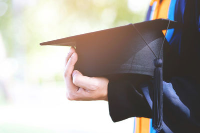 Midsection of student holding mortarboard