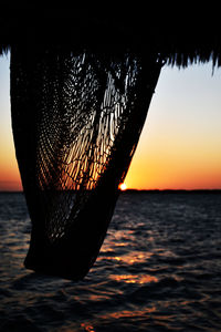 Close-up of silhouette tree by sea against sky during sunset