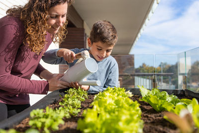 Mother and son watering vegetables in their urban garden