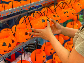 Woman choosing pumpkin jack o lantern at halloween accessories shop