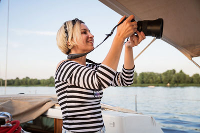 Pretty woman with camera taking pictures on a yacht