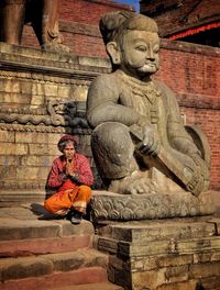 Statue of buddha sitting outside temple