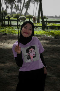 Portrait of a young woman standing on field