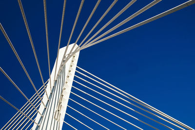 Low angle view of suspension bridge against blue sky