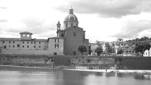 View of building by river against cloudy sky