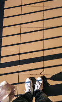 Low section of person on tiled floor during sunny day