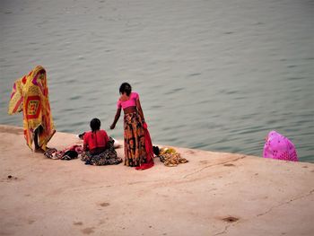 Rear view of people sitting on shore