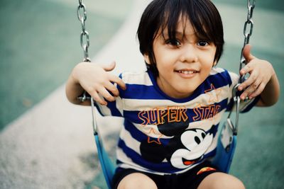 Portrait of smiling boy on swing at playground