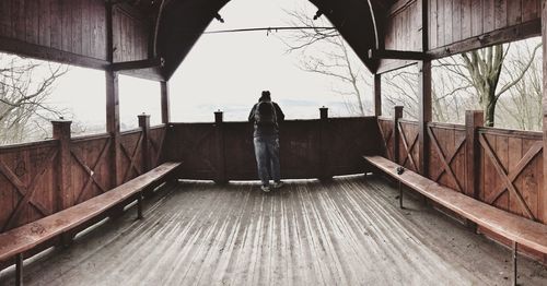 Rear view of man standing on railing in winter