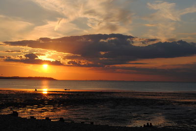 Scenic view of sea against cloudy sky during sunset