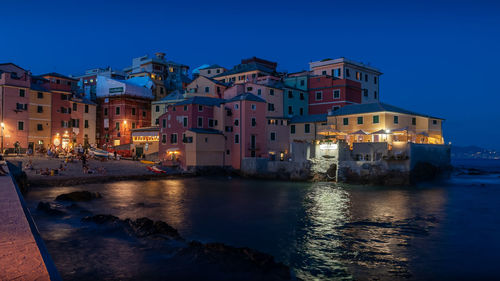 Buildings by sea against sky at dusk
